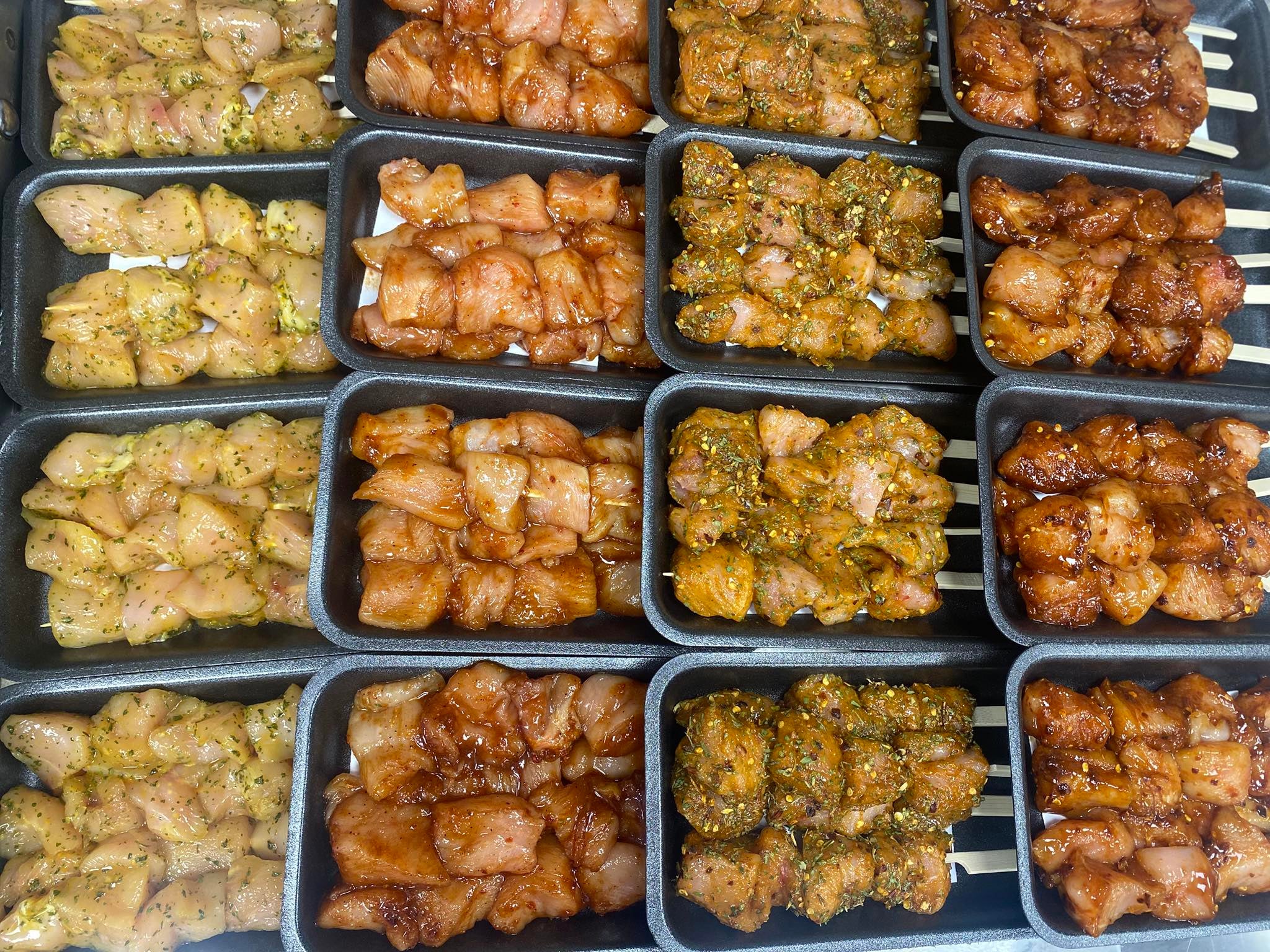 Assorted marinated chicken pieces in black containers.